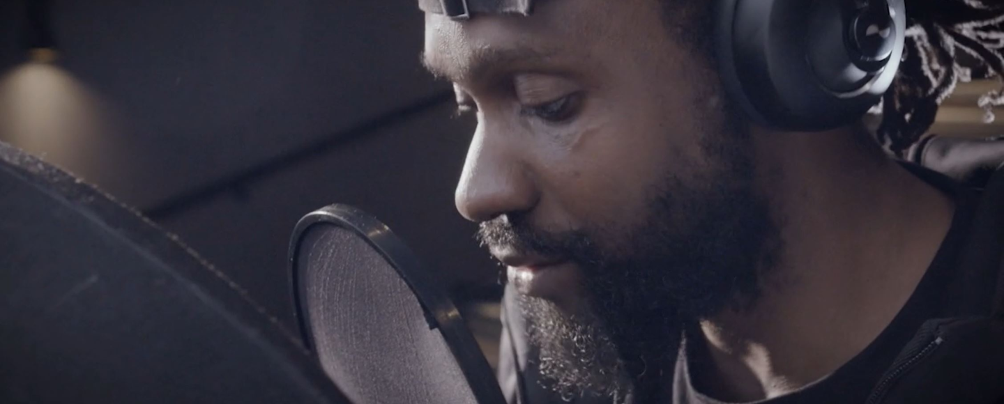 A singer/rapper with headphones on singing into a microphone