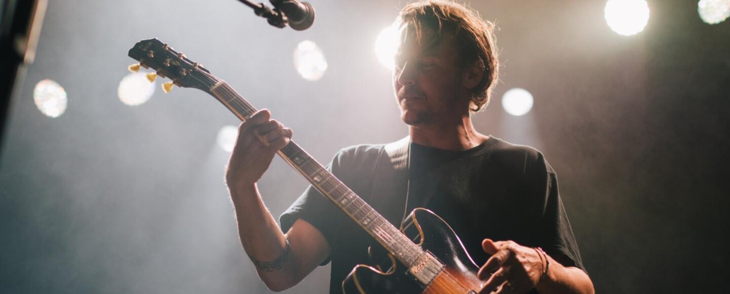 Musician playing the guitar and singing under a spotlight onstage