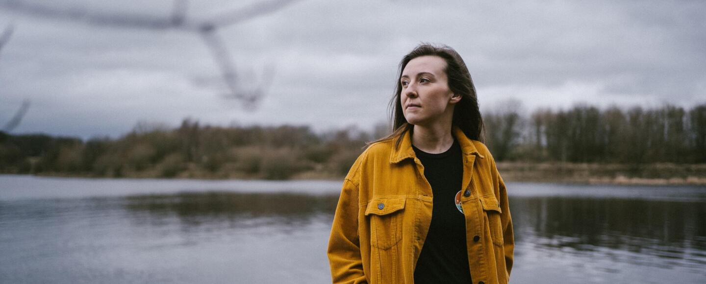 Emma Johnson standing by a lake on a cloudy day
