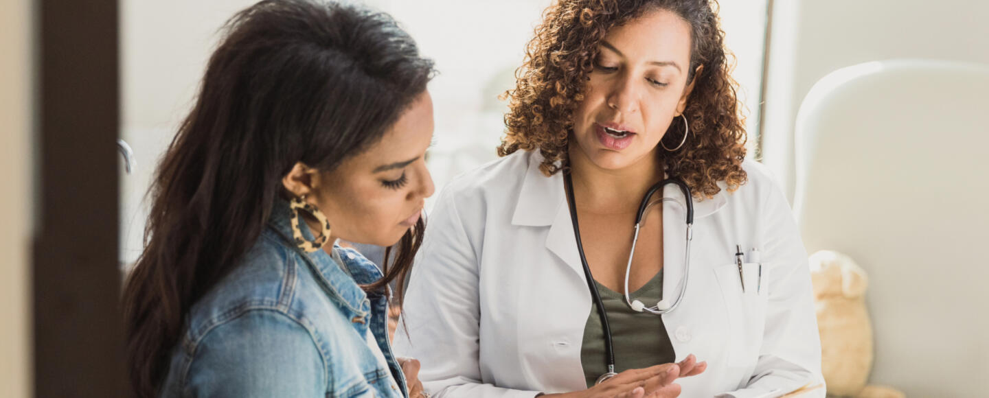 A doctor wearing a stethoscope shows a female patient some notes