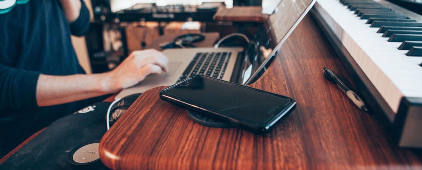 Music student sat a desk with a laptop and keyboard in front of them