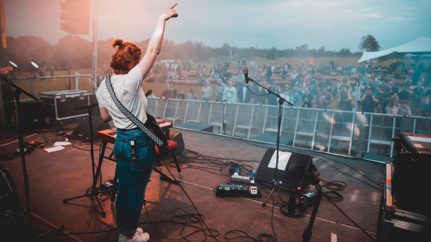 A guitarist performs in front of an outdoor audience