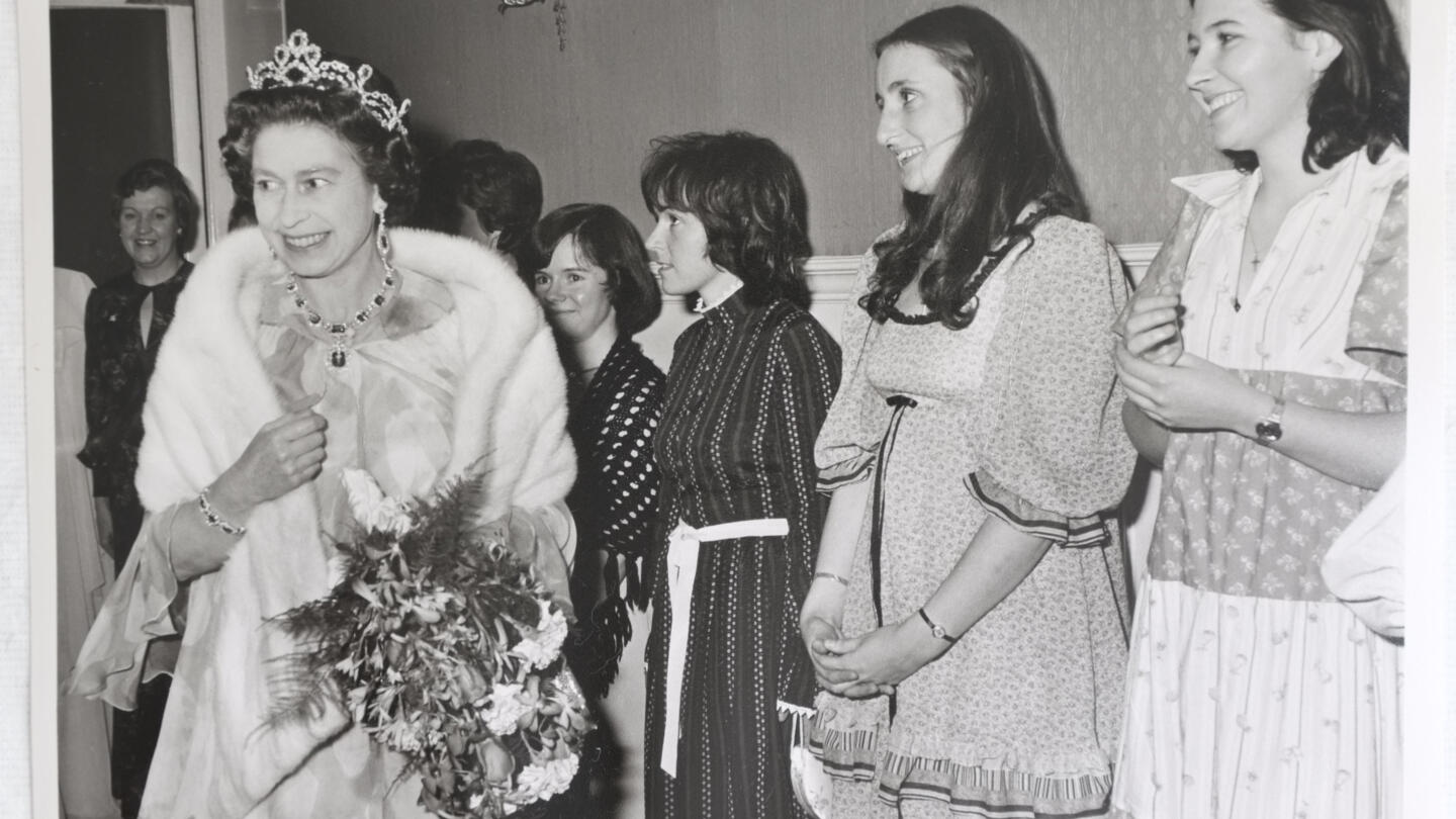 Queen Elizabeth greeted by a line of women as she arrives at fundraising concert