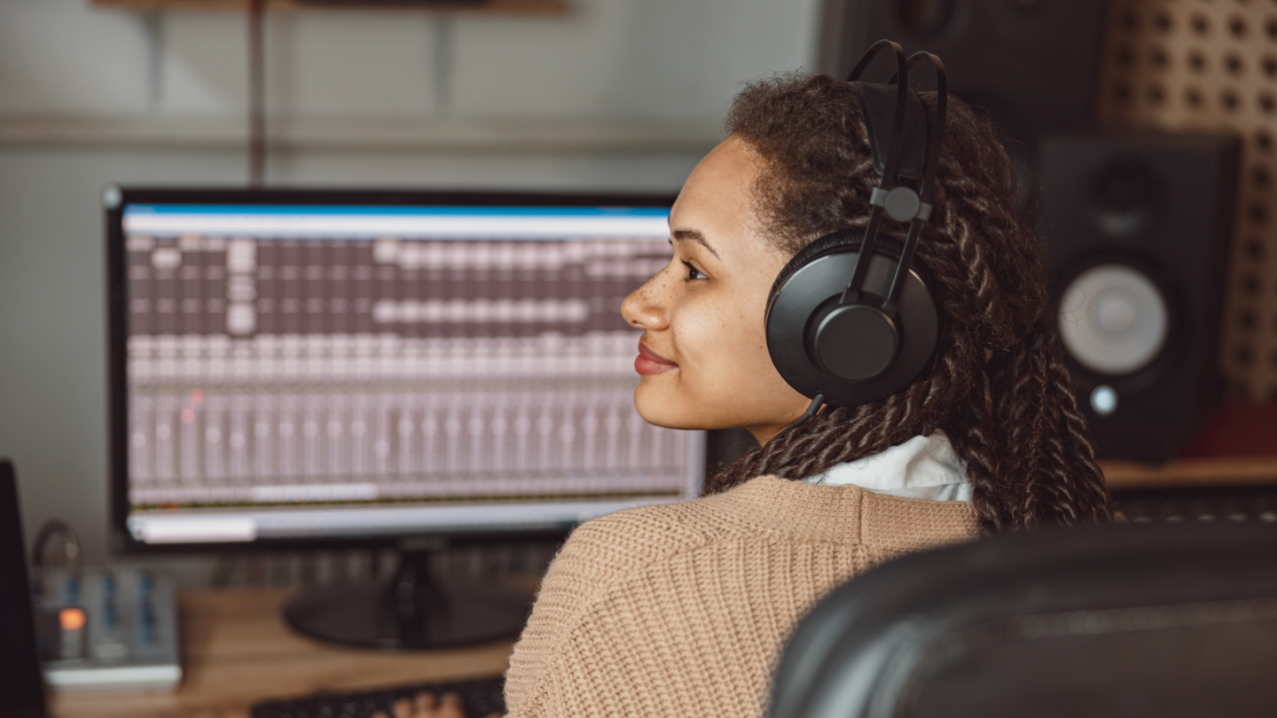A women wearing headphones recording music in a studio