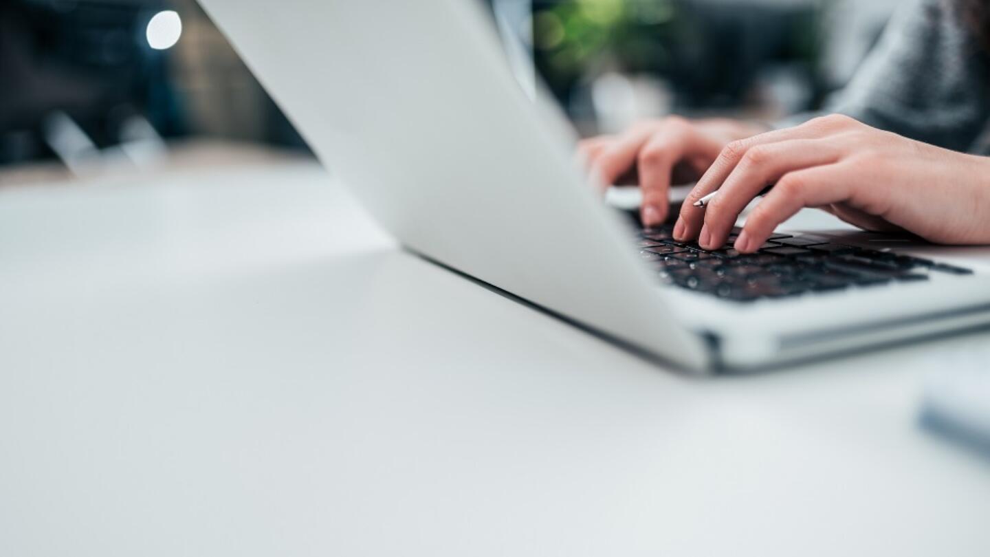 Hands typing on a laptop keyboard