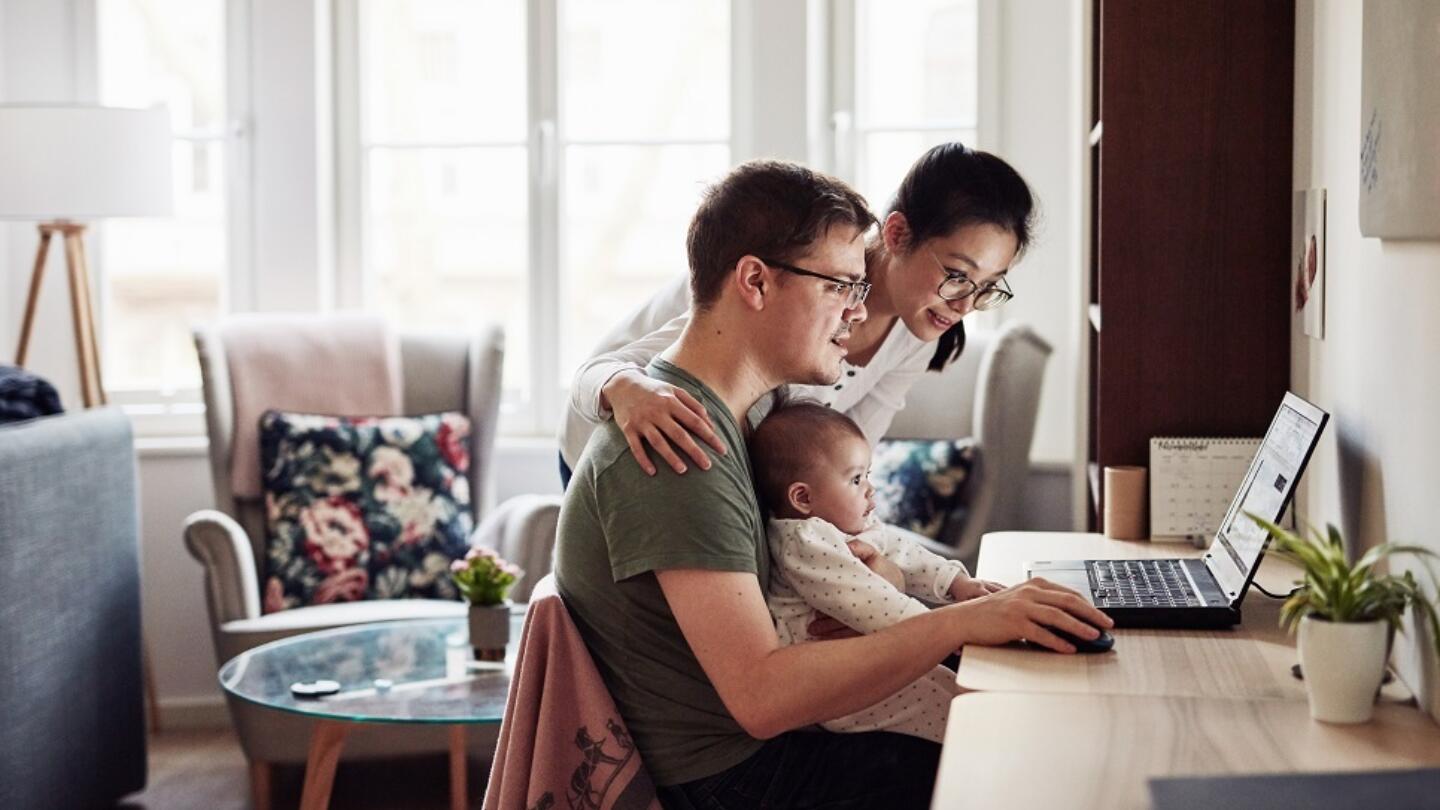 A family with a small child sit over a laptop