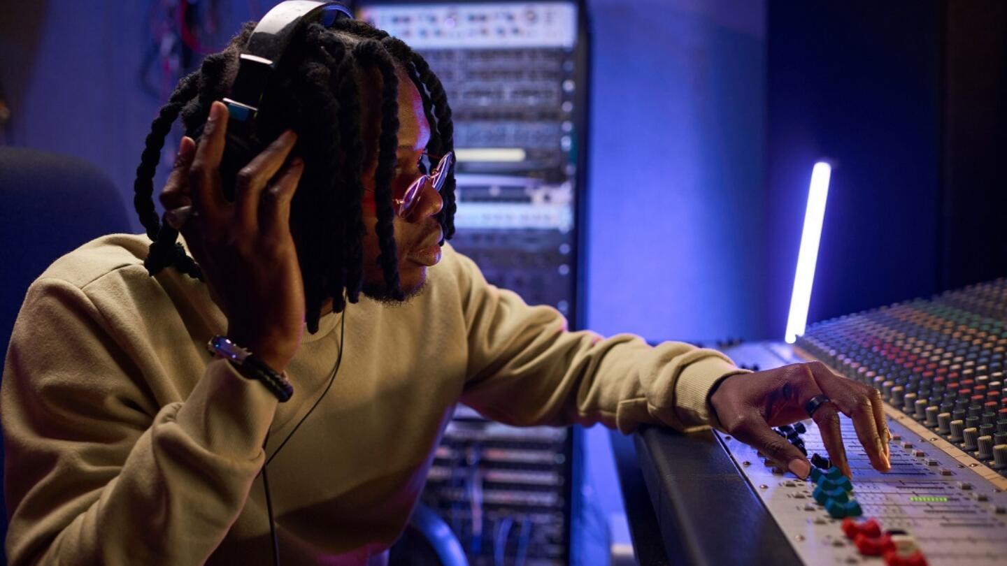 A musician sits in a recording studio wearing headphones