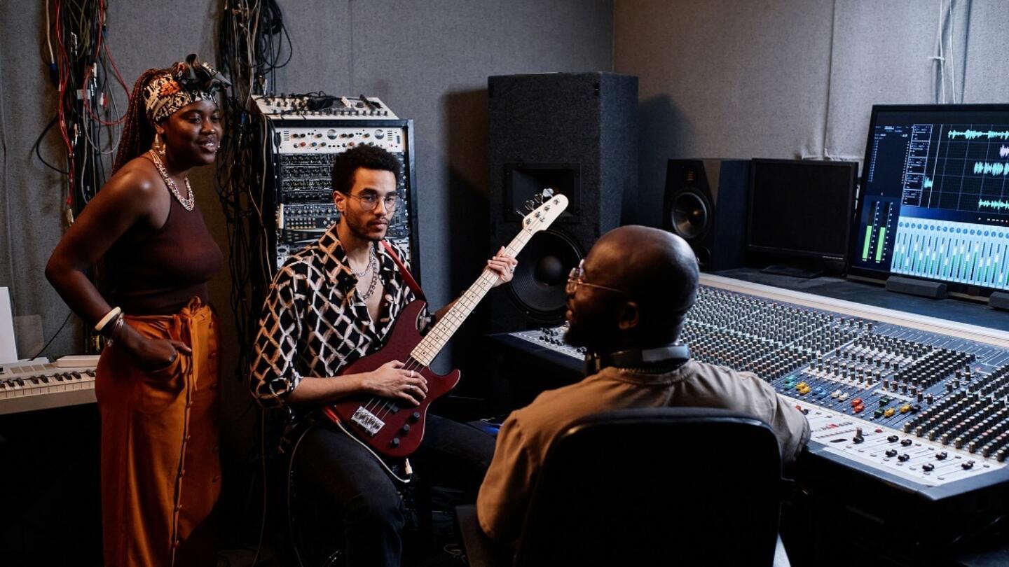 Three musicians talking together in a recording studio