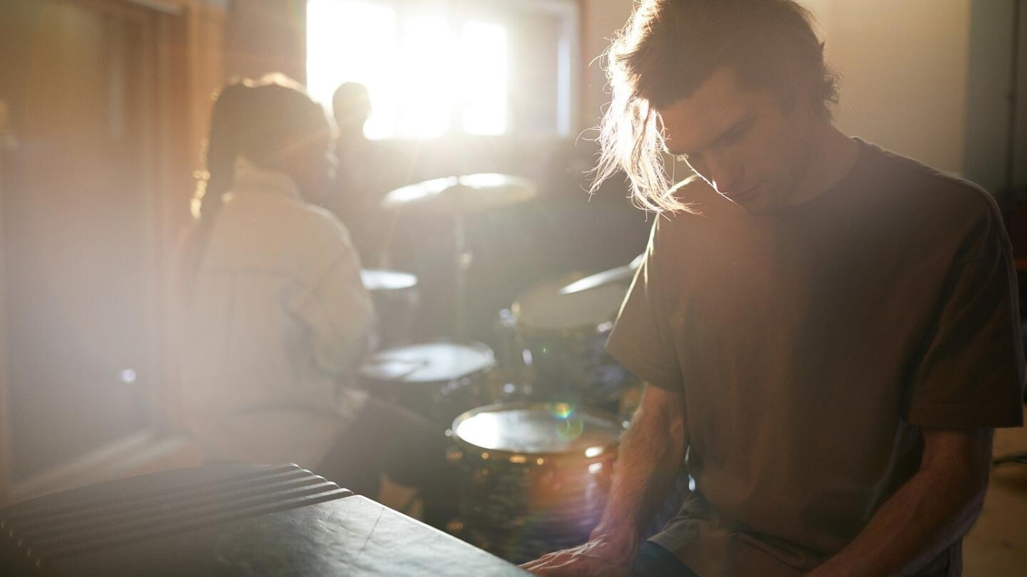 Musician plays a piano as the sun sets through a window