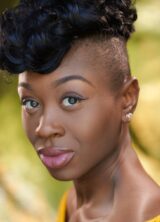 Close up headshot of Miriam-Teak Lee with greenery in the background