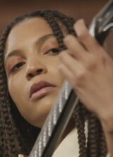 Sans Soucis looking at her hand as it forms a chord on the guitar
