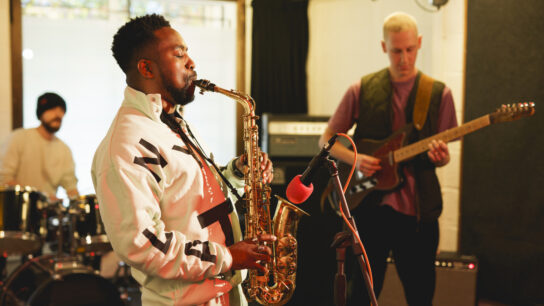 A jazz band playing together, comprising a saxophonist, bassist and drummer