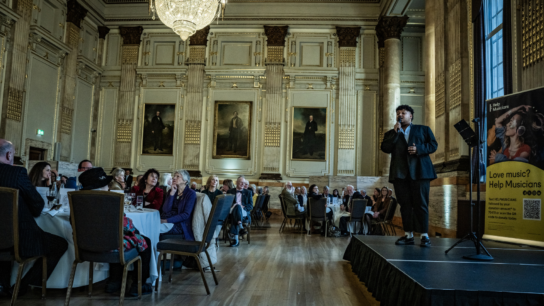 Singer Chad performing at the 2026 Festival of Cecilia luncheon service, entertaining guests seated at decorated dining tables.