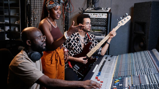 Three musicians talking together in a recording studio