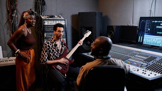 Three musicians talking together in a recording studio